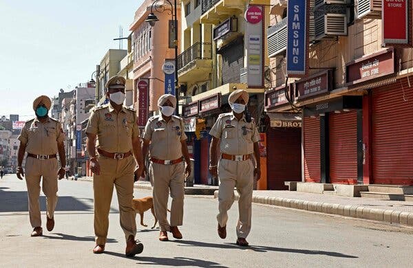 Police patrol a deserted market area during the lockdown imposed by the state government in Amritsar, India, on Saturday.