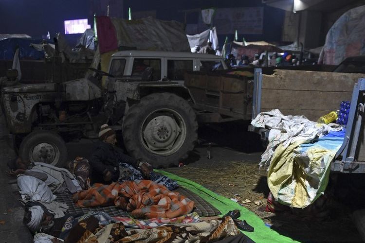 Demonstan petani India, berkemah di tempat terbuka dengan traktor dan trailer yang diparkir berdempetan melawan musim dingin yang keras di India Utara