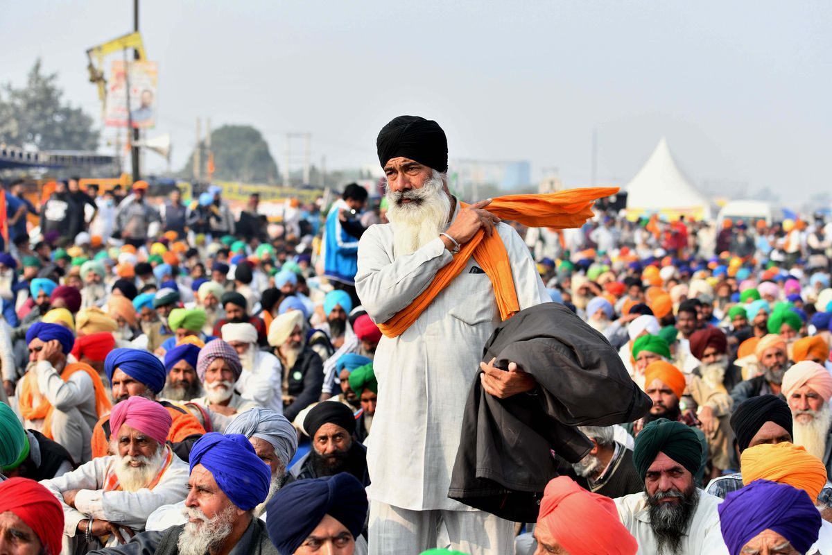 An Indian farmer stands in the middle of a sitting crowd at a protest against India’s new farm laws in December 2020.