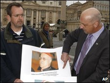 John Pilmaier from Milwaukee, left, and Peter Isely of the SNAP bureau (Survivors Network of those Abused by Priests) show pictures of Pope Benedict XVI, left, and of cardinal Tarcisio Bertone during a press conference in front of the Vatican Thursday, March 25, 2010